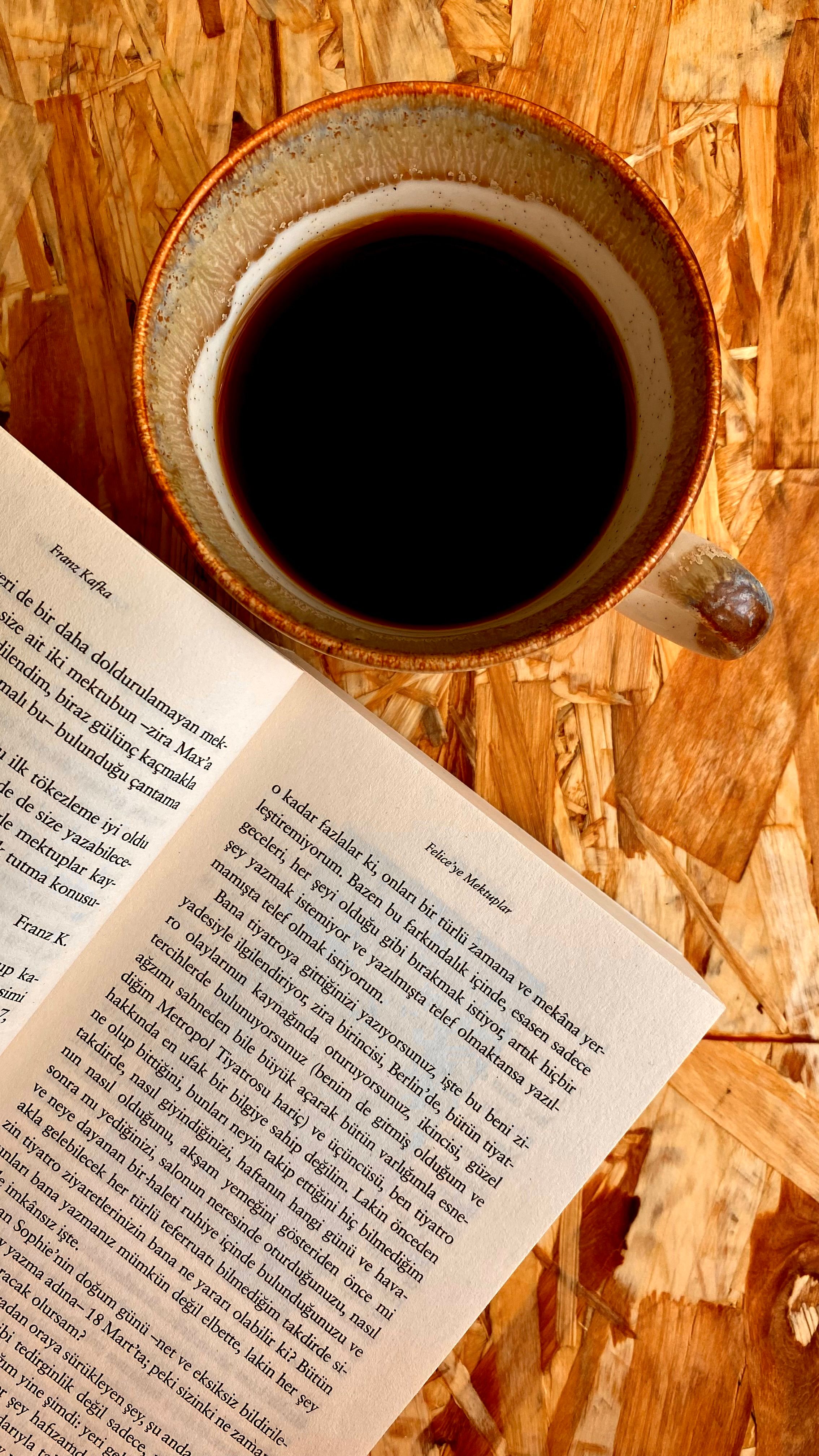 Coffee cup and open book on wooden surface creating a cozy reading nook.