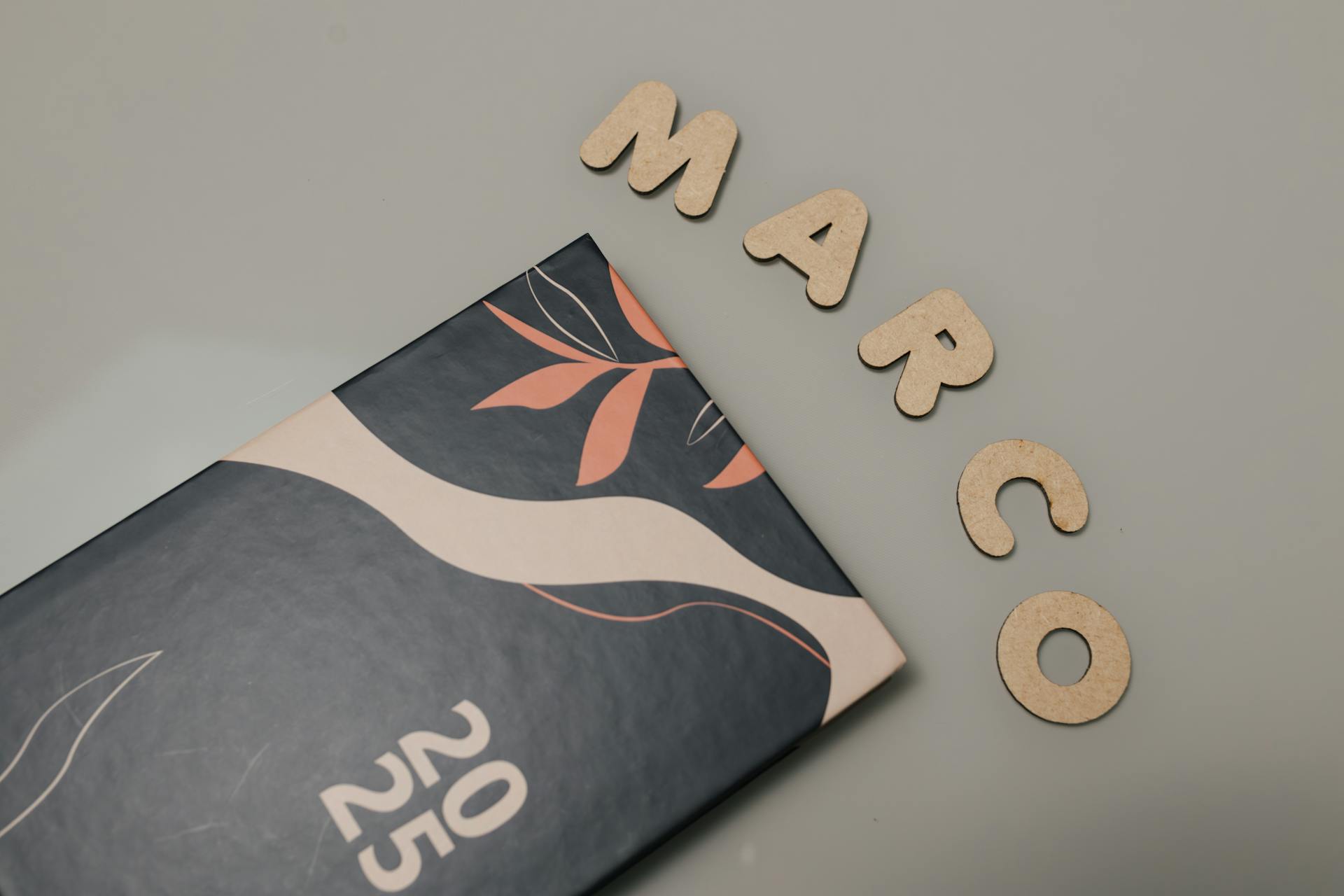 Creative flat lay of a 2025 notebook and cutout letters on a beige surface, perfect for organization visuals.