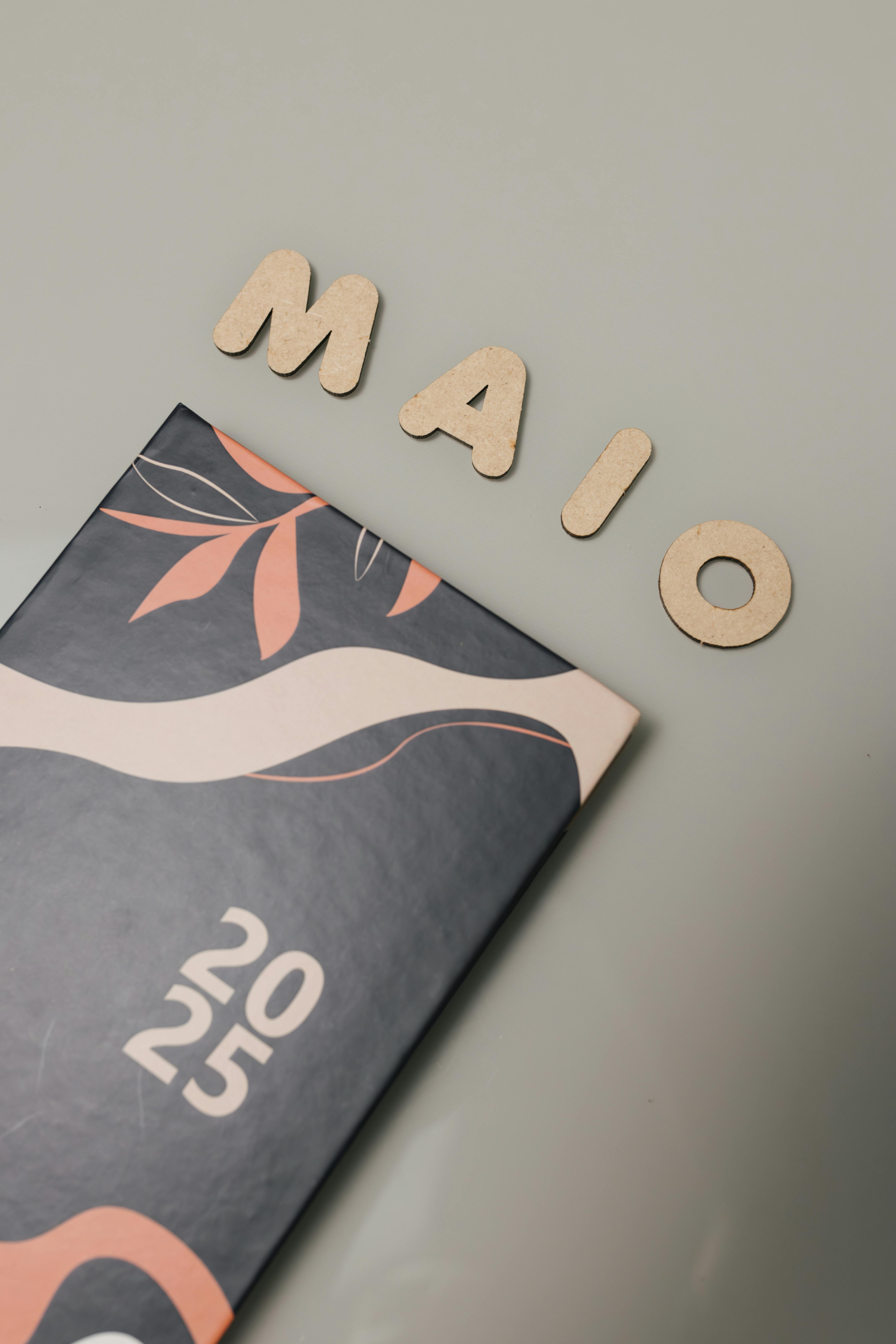 Kostenlos Stilvoller Kalender 2025 mit „MAIO“-Holzbuchstaben auf minimalistischem Hintergrund. Stock-Foto