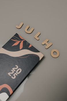 2025 calendar with wooden letters spelling 'Julho' and artistic floral design.