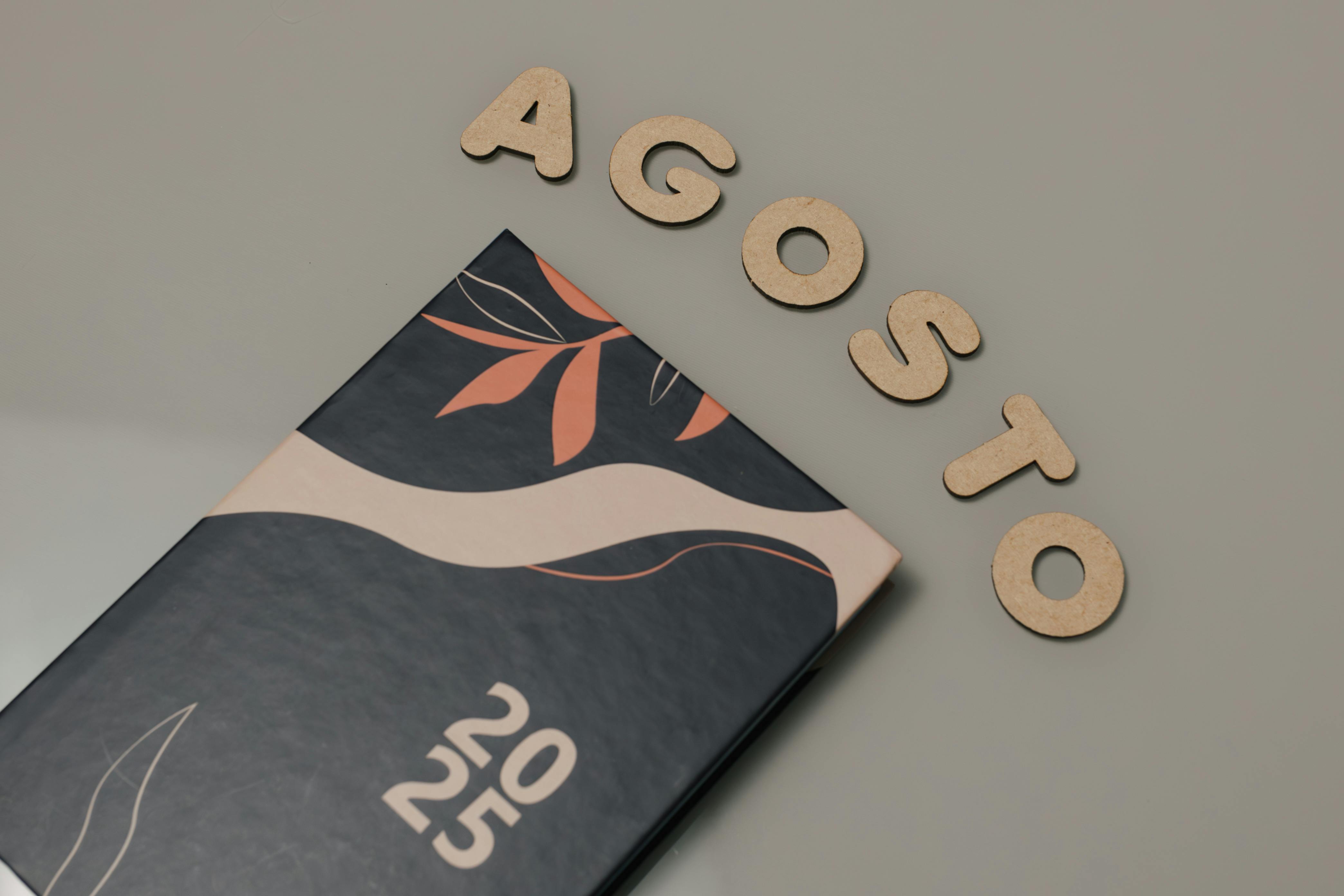 grátis Uma agenda estilosa para 2025 com capa artística e letras "Agosto" em uma superfície plana. Foto profissional