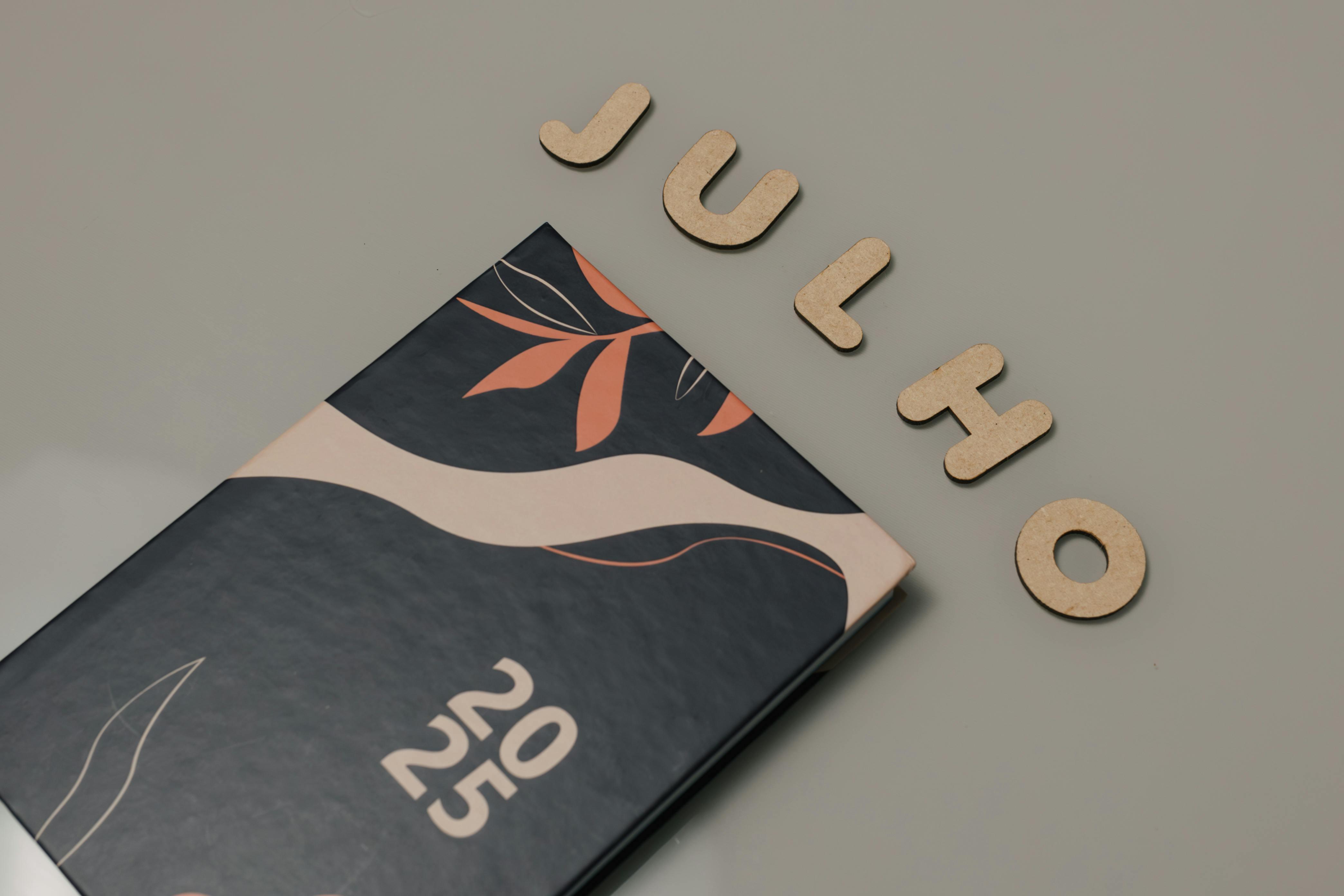 무료 중립적인 표면에 나무 글씨로 'Julho'가 적힌 세련된 2025년 플래너입니다. 스톡 사진