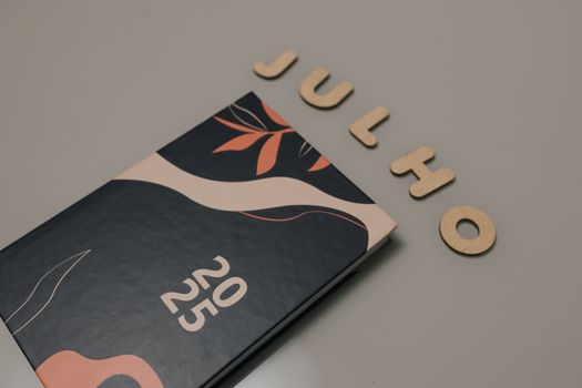 A 2025 planner with a modern design, next to wooden letters spelling 'Julho'.