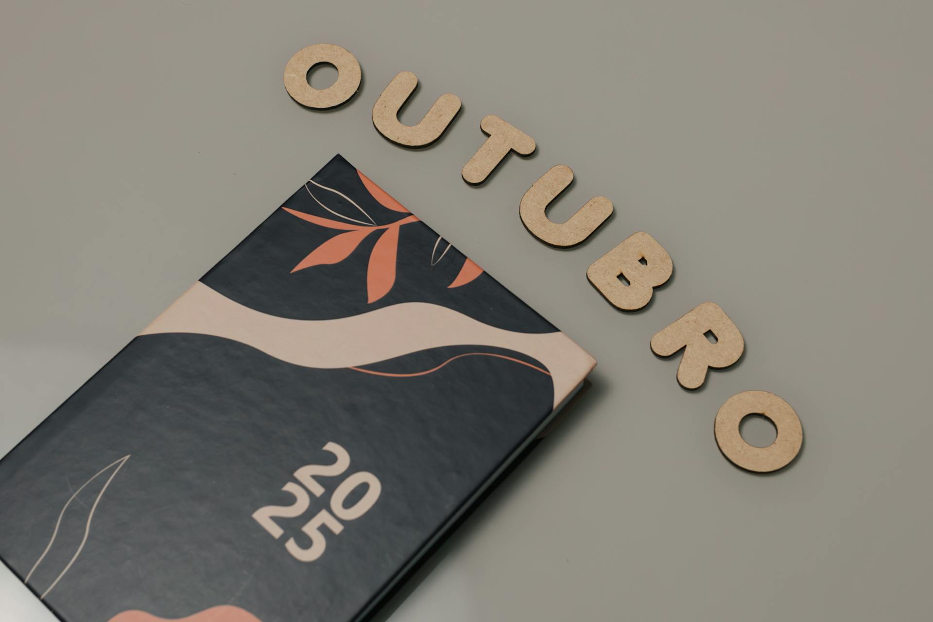 2025 planner and 'Outubro' in wooden letters on a desk for organization and planning.