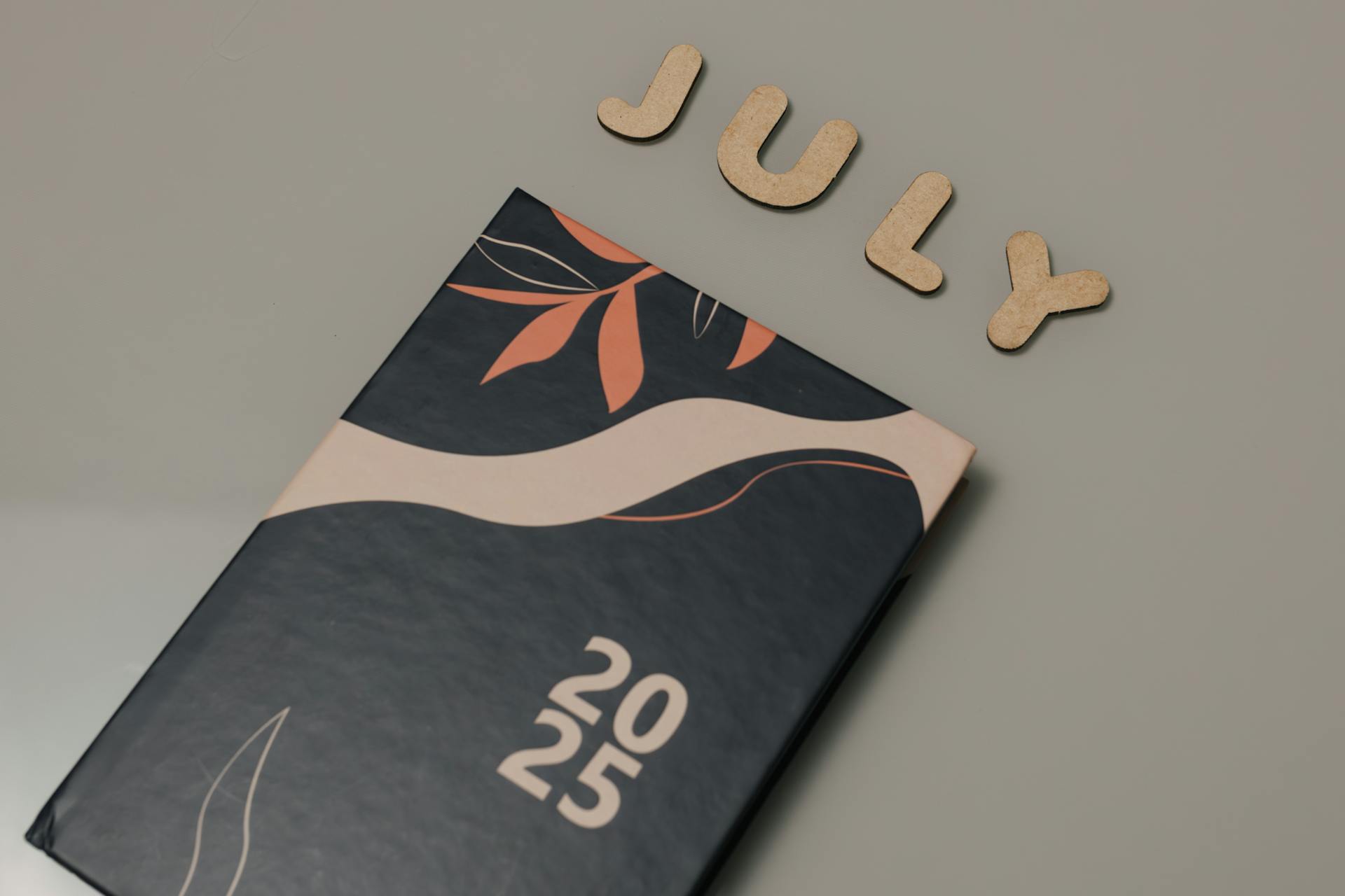 Close-up of a 2025 planner with July letters on a minimalist background.