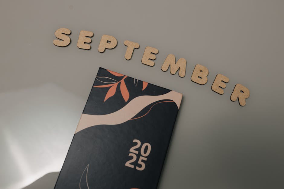 Flat lay of a 2025 calendar with September in wooden letters and an autumn design on a neutral background.