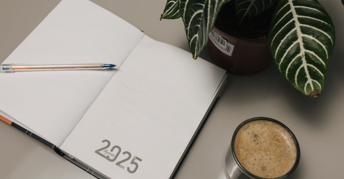 Open planner with a cup of coffee and a small plant on a warm desk, representing the quiet morning routine of a family law office.