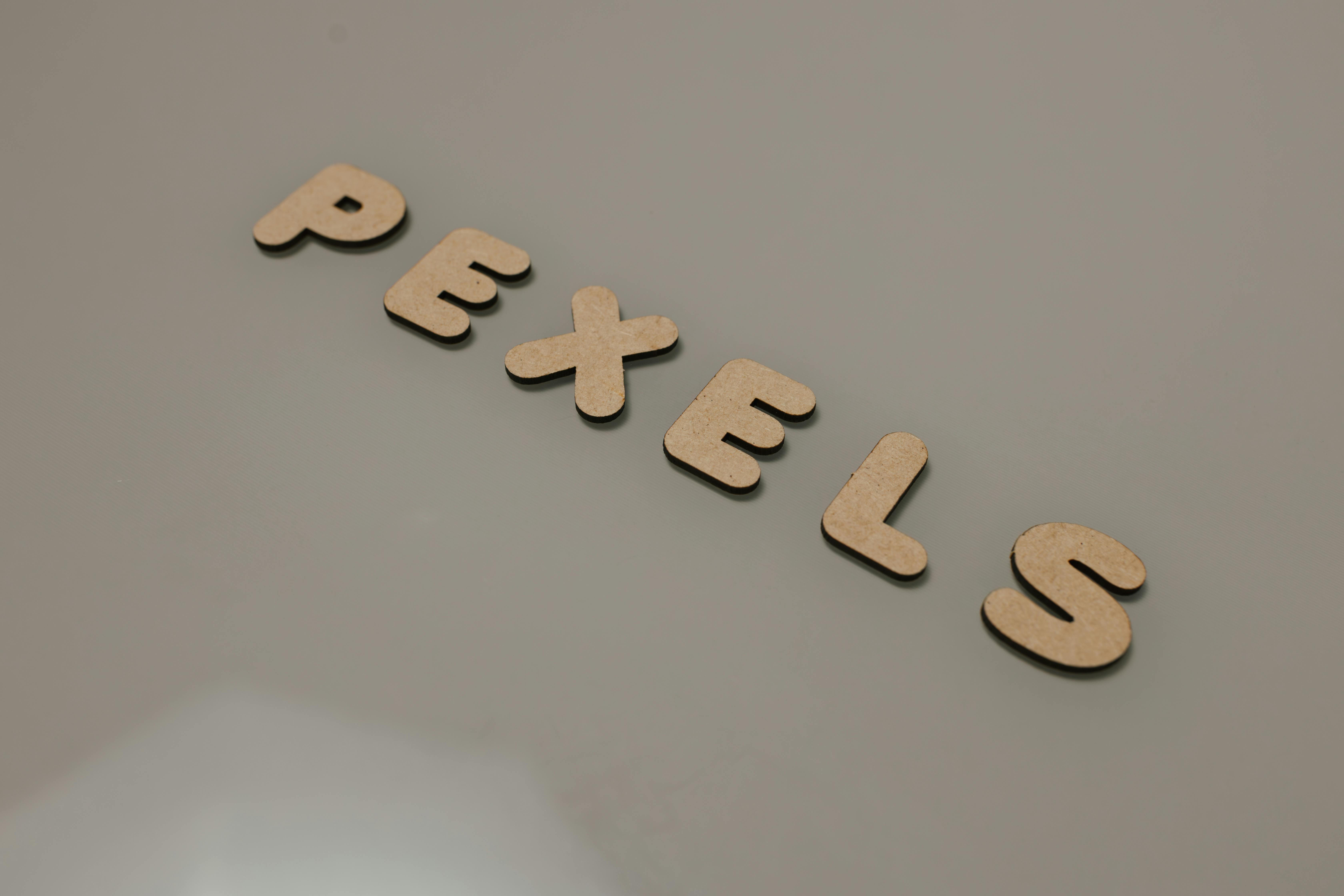 Gratis Minimalistisk design med trebokstaver som staver 'Pexels' på en jevn grå bakgrunn. Arkivbilde