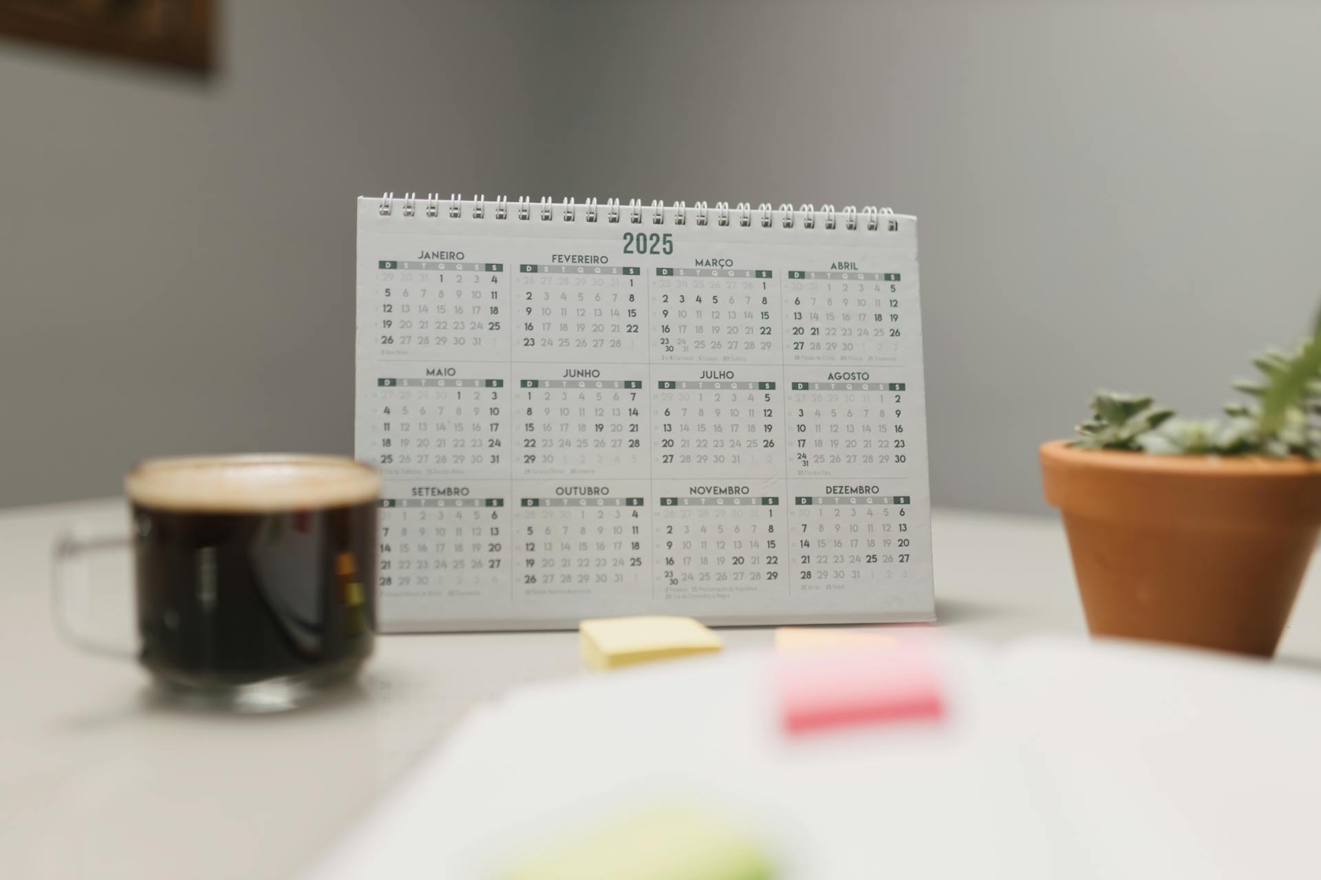 A 2025 desk calendar with coffee and succulent, ideal for planning and office decor.