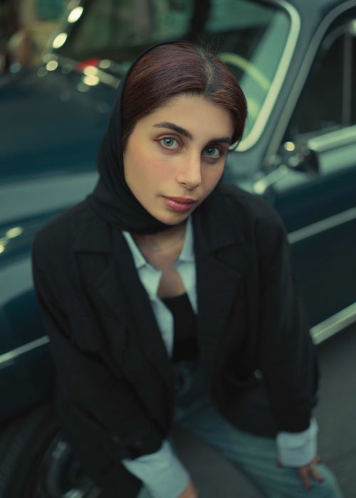 Free Portrait of a stylish young woman in hijab posing confidently next to a vintage car. Stock Photo