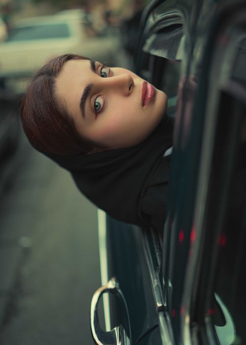 Free A young woman with striking eyes gazes out of a car window, creating a dramatic portrait. Stock Photo