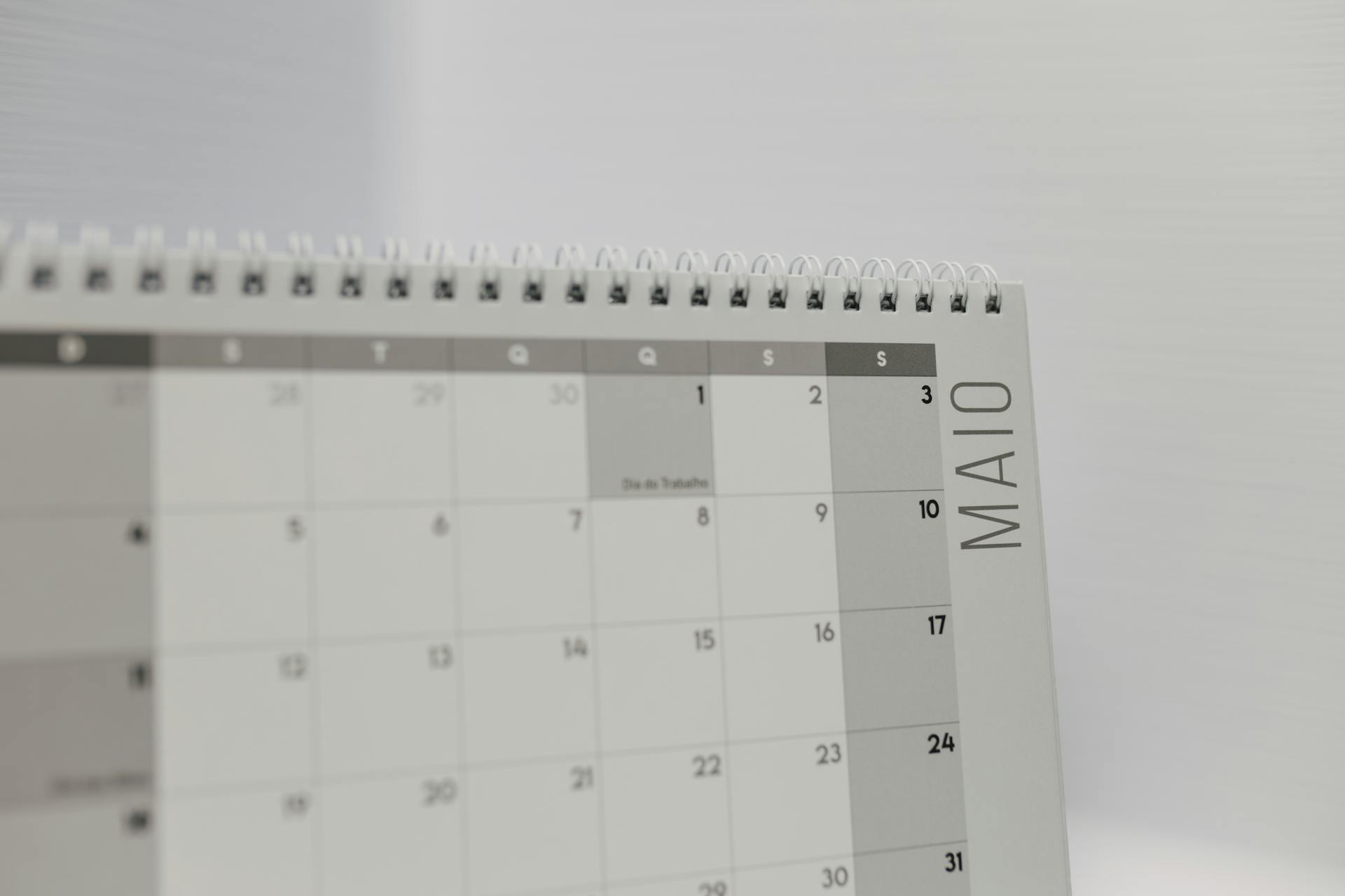 Spiral-bound calendar showing May with focus on weekdays in Portuguese.