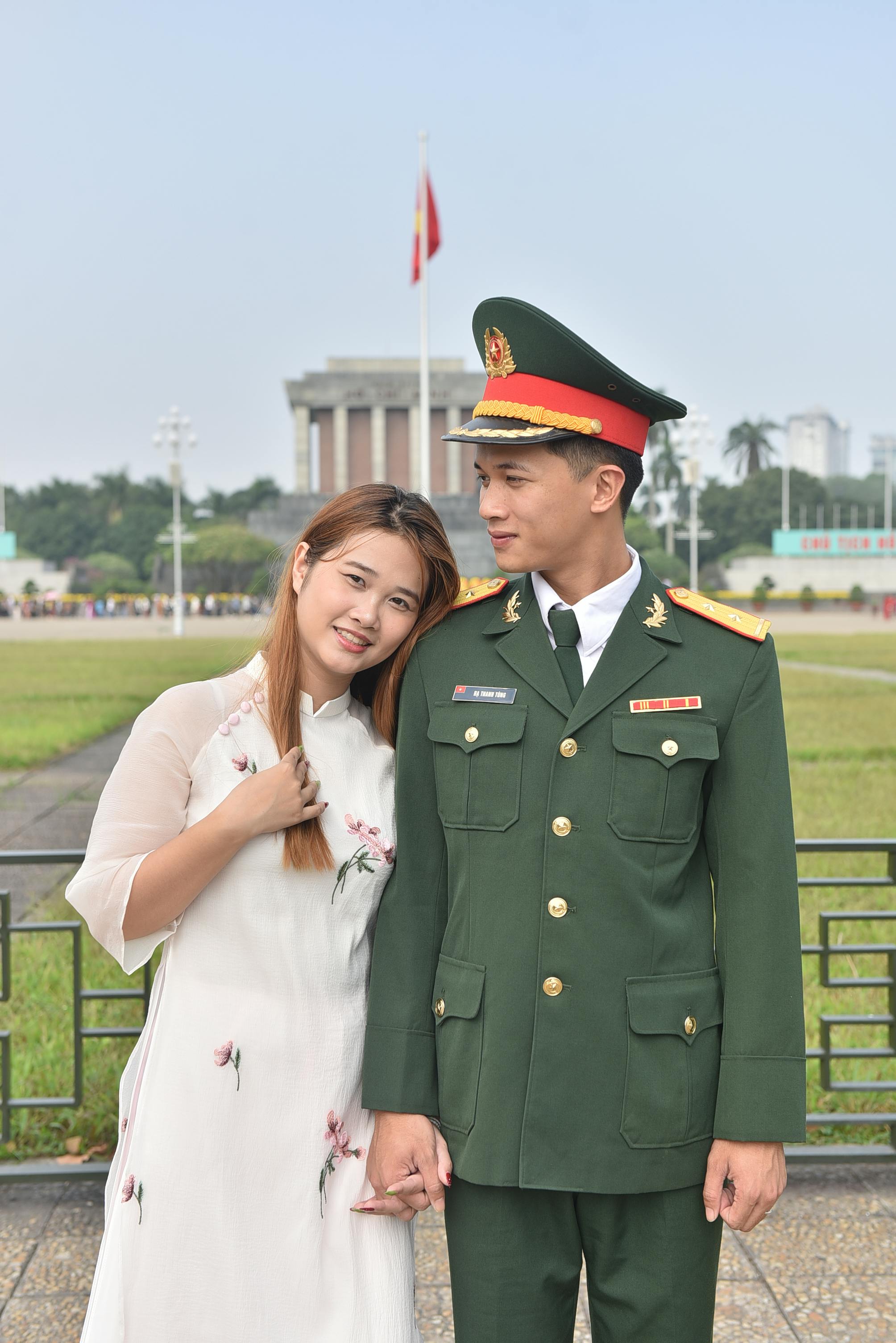 A couple, one in military uniform, poses before a historic building.