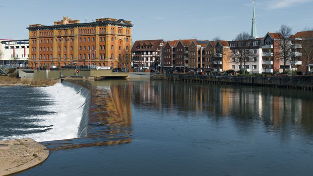 Idyllic riverside view with historic buildings in Hameln, Germany.