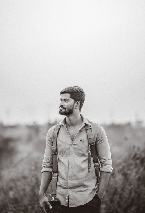 Free Black and white portrait of a young photographer outdoors holding a camera. Stock Photo