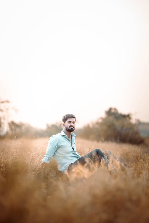 Free Young man relaxing outdoors in a sunlit field, serene and peaceful scene. Stock Photo