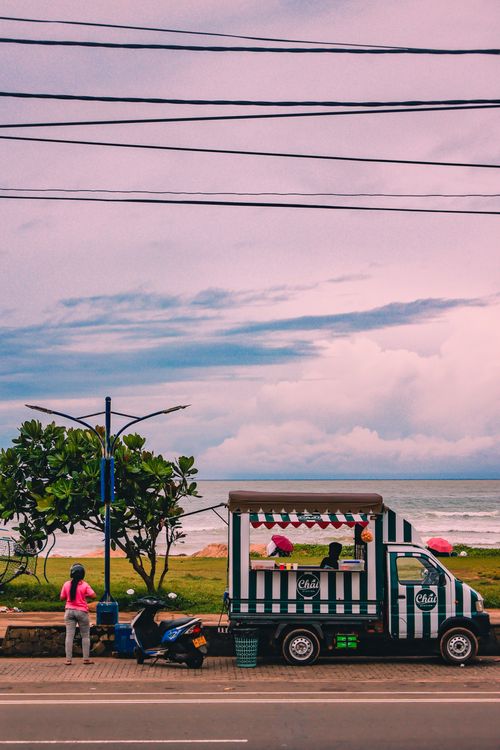 Free Colorful food truck by the coast in Sri Lanka offering local delicacies with an ocean view. Stock Photo