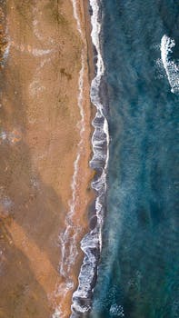 Top-down drone shot of a wave-swept sandy beach in Ünye, Türkiye.