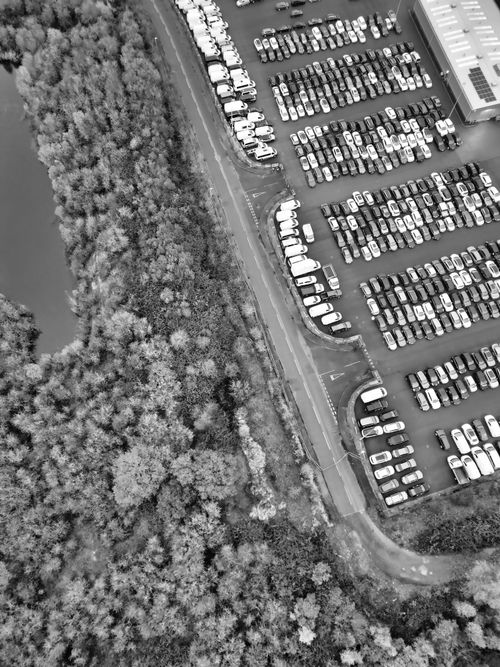 Free Aerial photograph showcasing a car park adjacent to a natural landscape, captured in black and white. Stock Photo