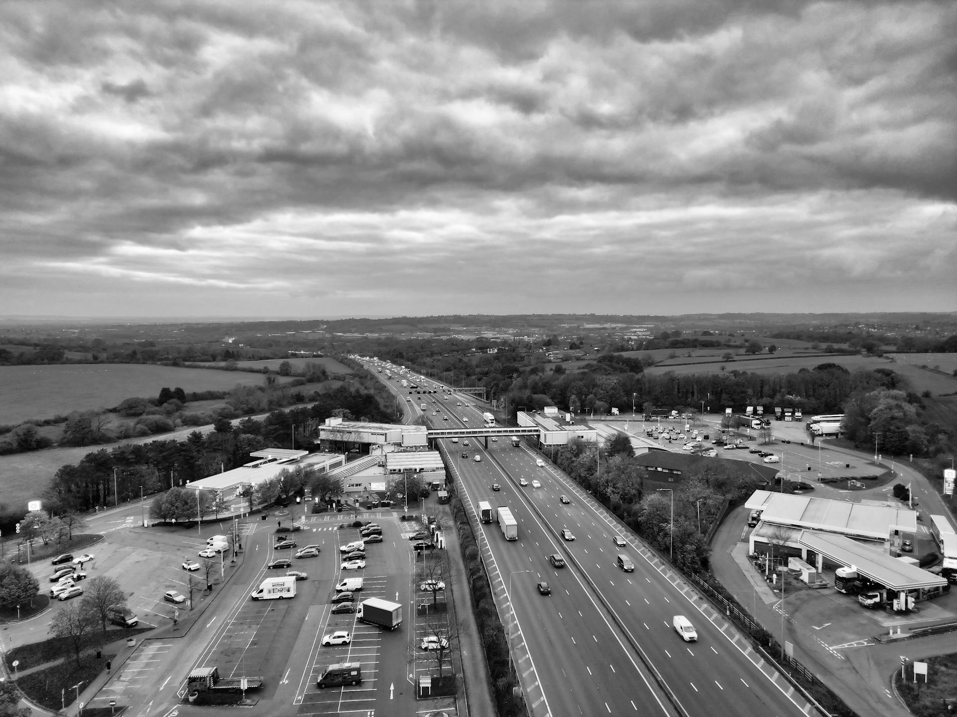 A dramatic aerial shot of the M1 Motorway surrounded by lush countryside under a cloudy sky.