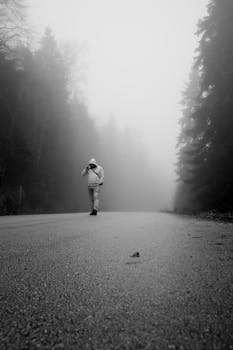 A solitary figure walks down a foggy forest road in Bolu, Türkiye, evoking mystery.