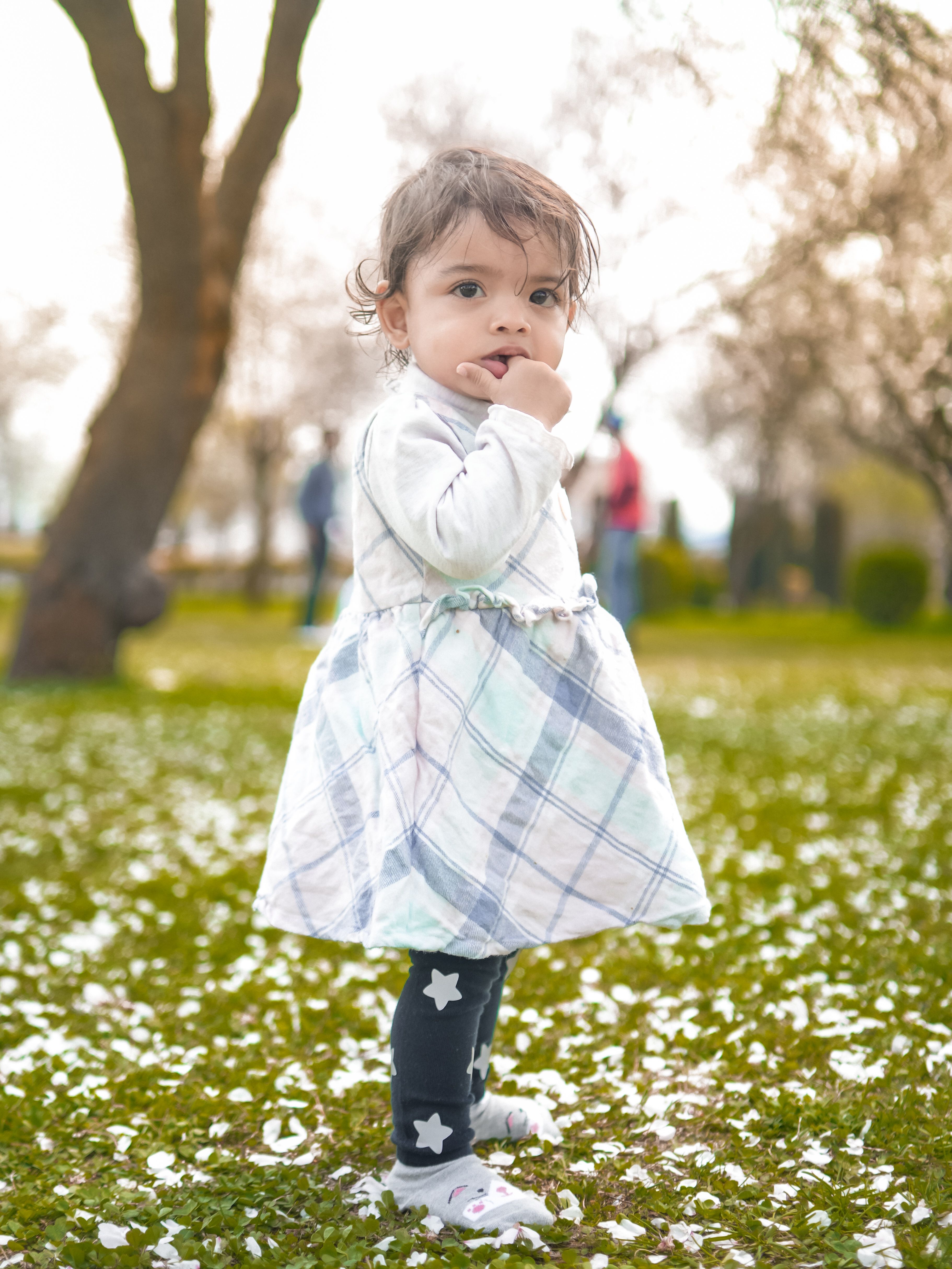 A little girl in a blue dress is standing in front of a bench · Free ...