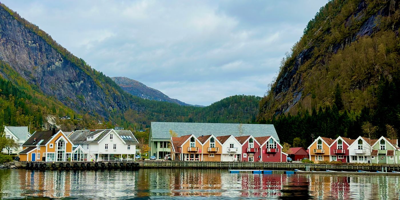 Colorful houses reflected in a calm Norwegian fjord with mountains behind
