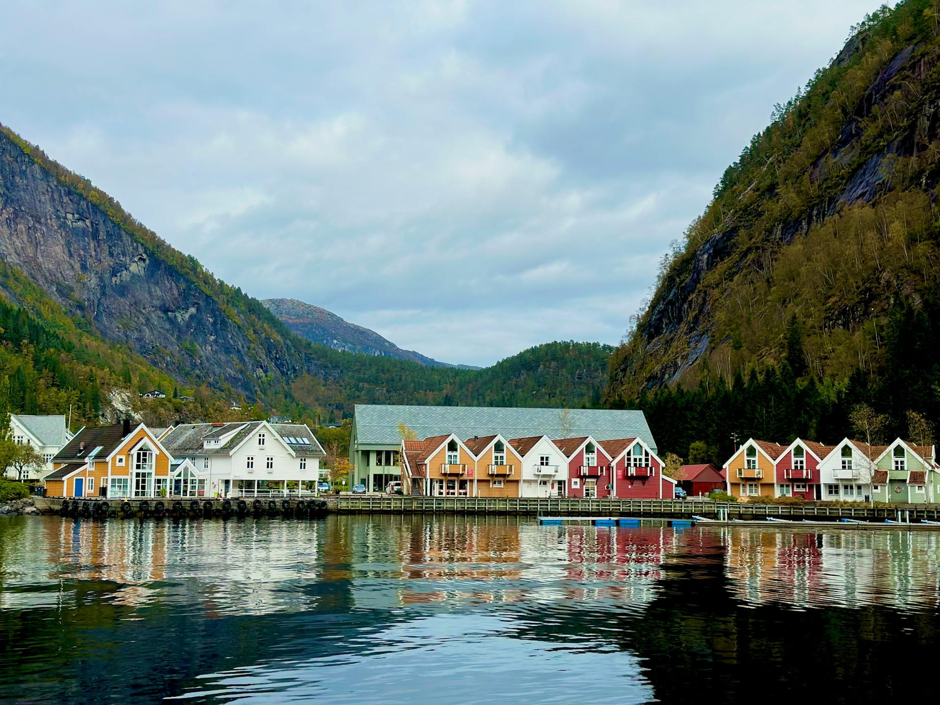 Scenic view of colorful houses by a Norwegian fjord with mountain reflections.