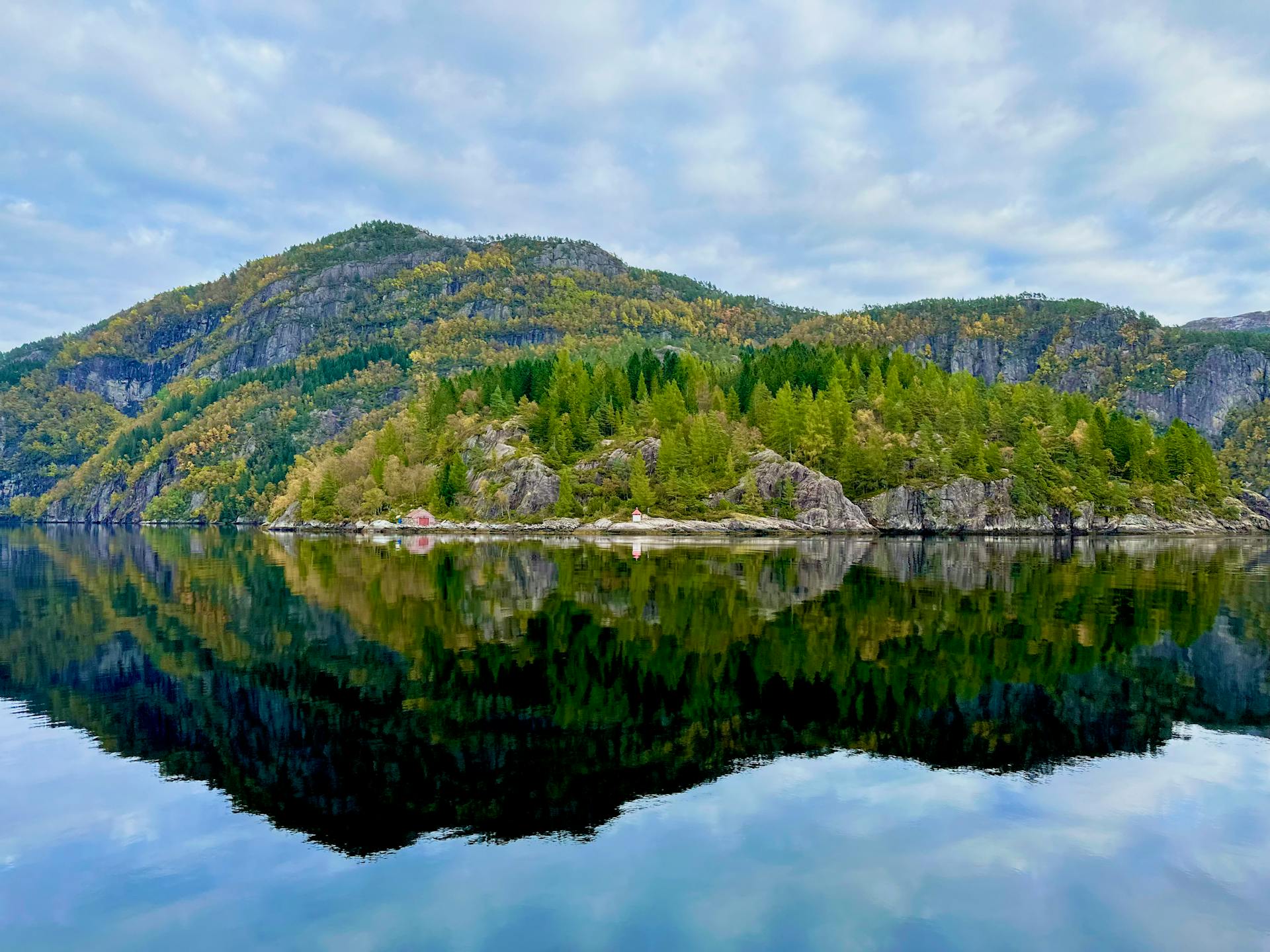 Stunning reflection of a Norwegian fjord landscape with autumn foliage.