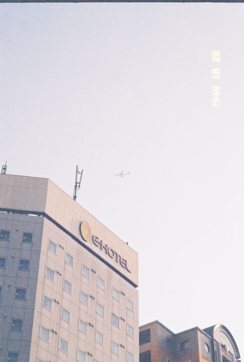 Free An airplane flies over a city hotel building under a bright sky. Stock Photo
