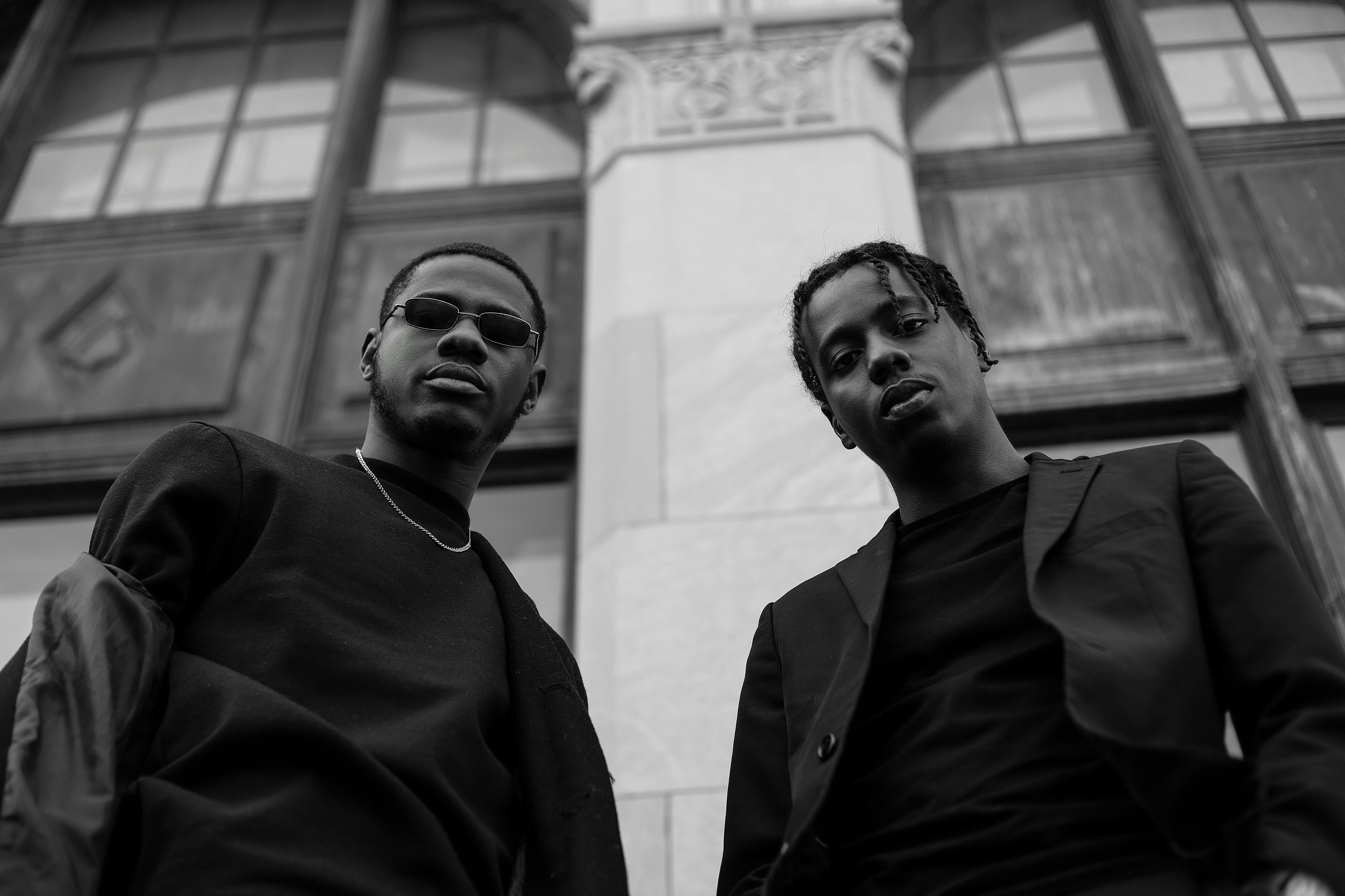 Grayscale Photography Of Two Men Standing Near Building Free
