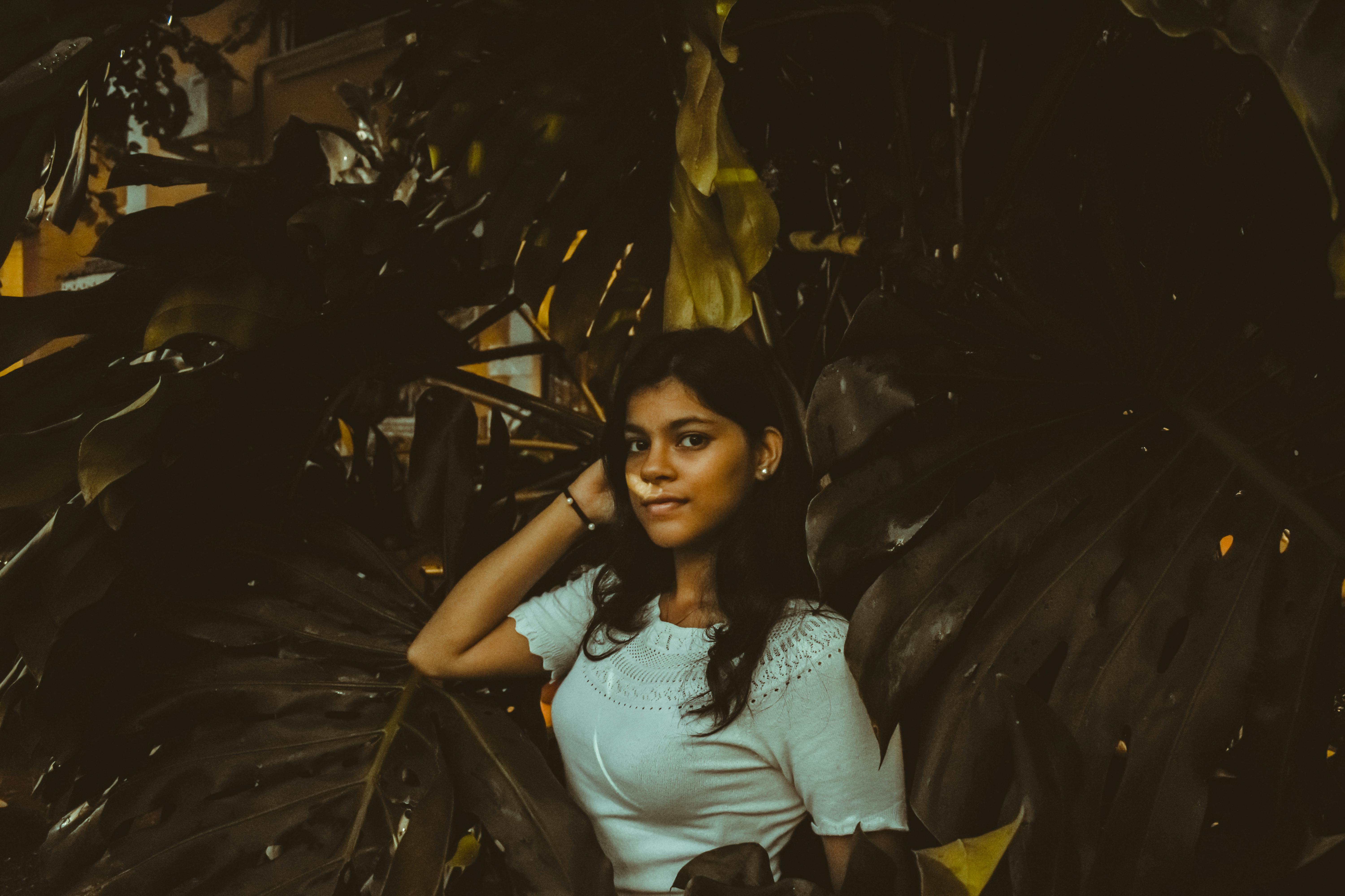 一位年轻女子在郁郁葱葱的热带树叶间自信摆姿，唤起一片宁静心境