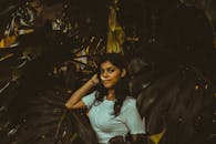 一位年轻女子在郁郁葱葱的热带树叶间自信摆姿，唤起一片宁静心境