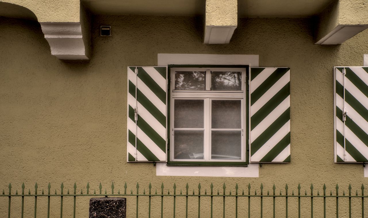 classic green and white striped window shutters on a residential build