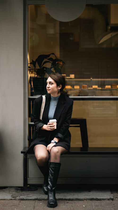 Free Fashionable young woman sitting outside café with coffee cup. Stock Photo
