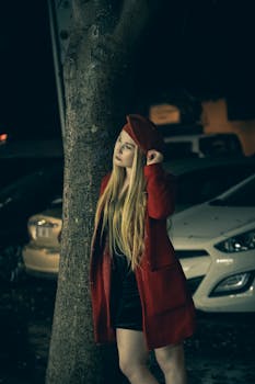 Elegant woman standing by a tree at night during rain in Adana. Captured with a Canon EOS 6D Mark II.