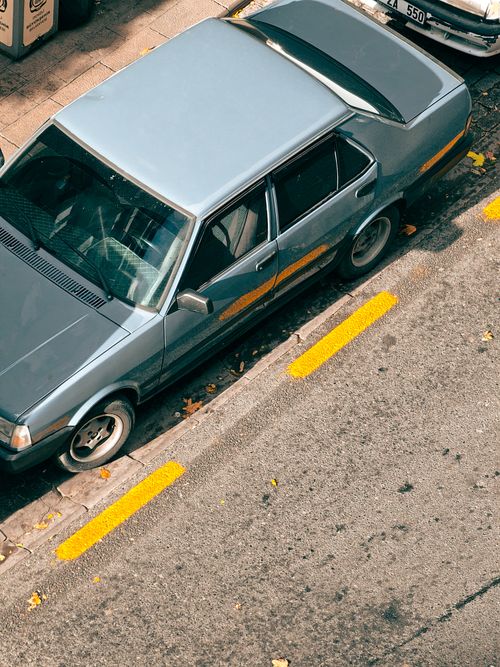 Free Aerial view of a vintage blue car parked on a sunlit urban street. Stock Photo