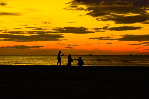 Free Silhouette of people enjoying a beautiful sunset on the beach in Bayawan City, Philippines. Stock Photo