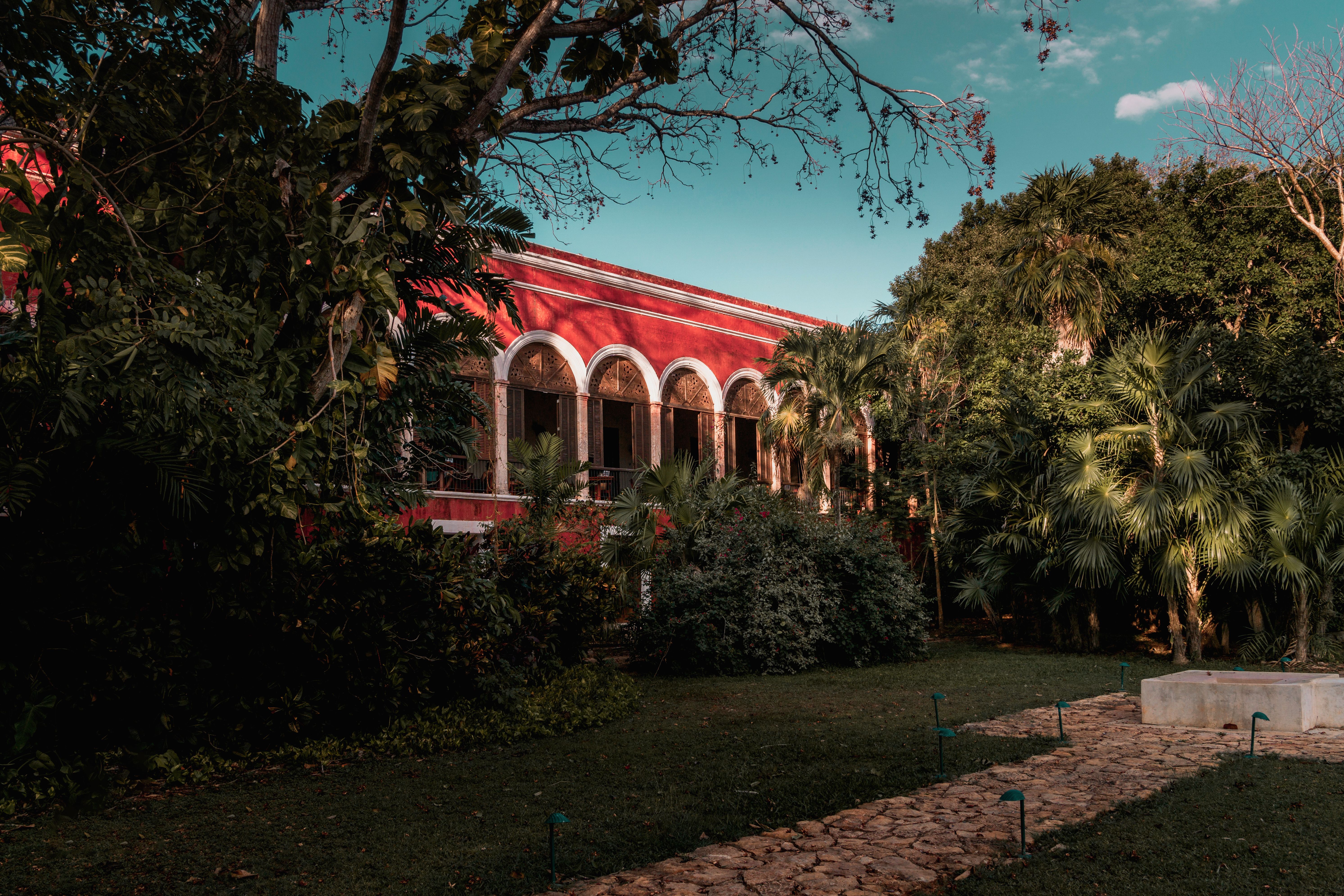 Portales rojos de una hacienda henequenera restaurada entre palmeras y jardines en Temozón Sur, una de las haciendas de Yucatán al sur de Mérida