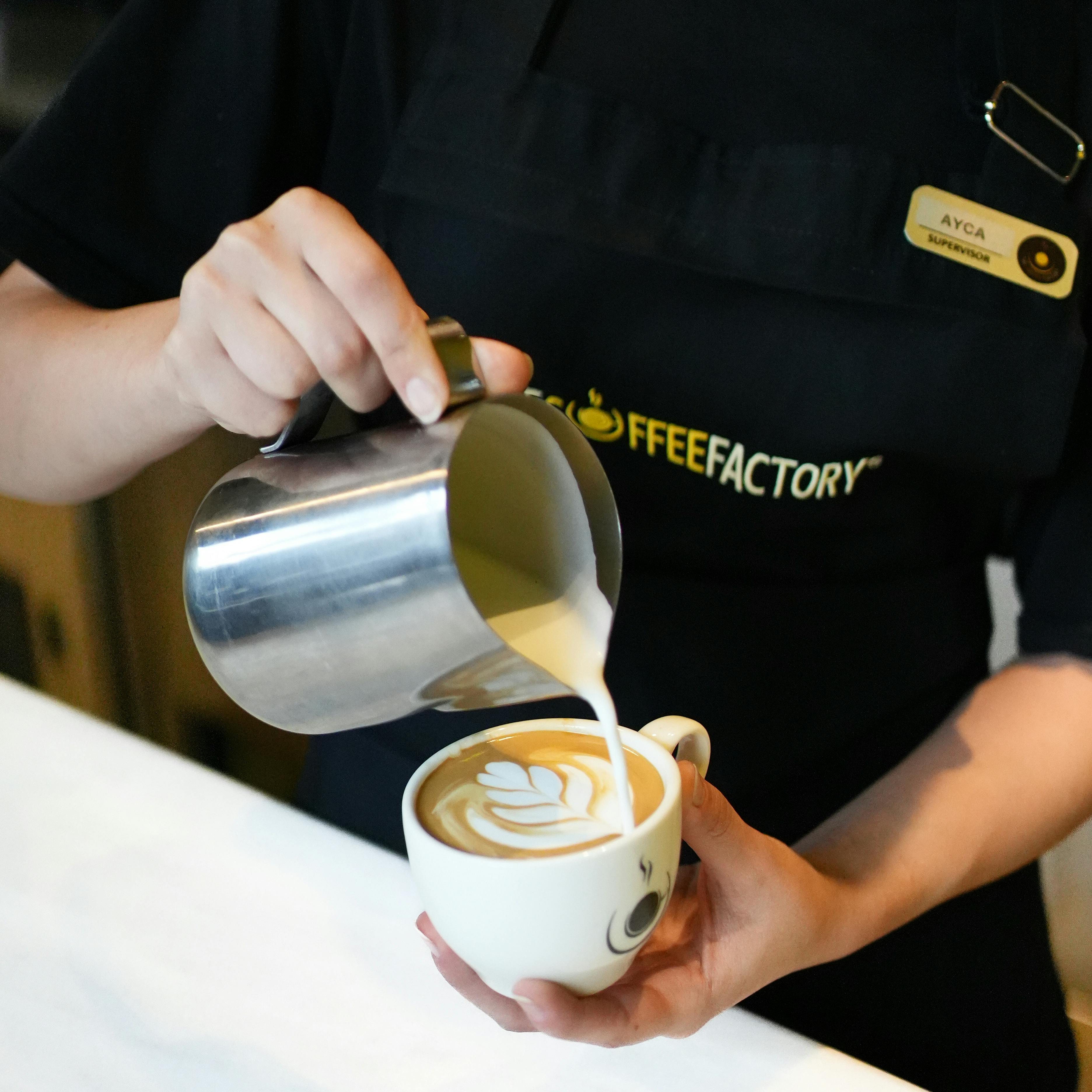 Barista pouring latte art on a flat white at a specialty cafe in Singapore