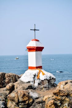 A distinctive cross atop rocks at Vagator Beach, Goa with ocean view.