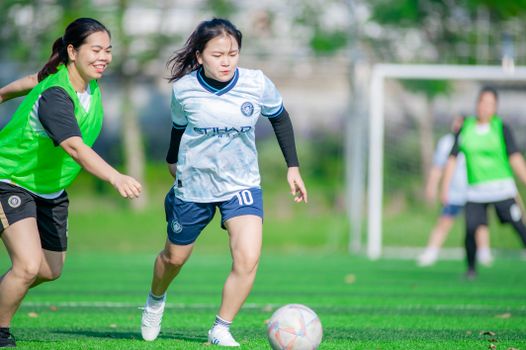 Female soccer players in action during a sunny match in Hà Nội, Vietnam.