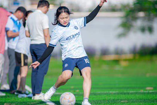 A young female soccer player skillfully kicking the ball on an outdoor field in Hanoi, Vietnam.