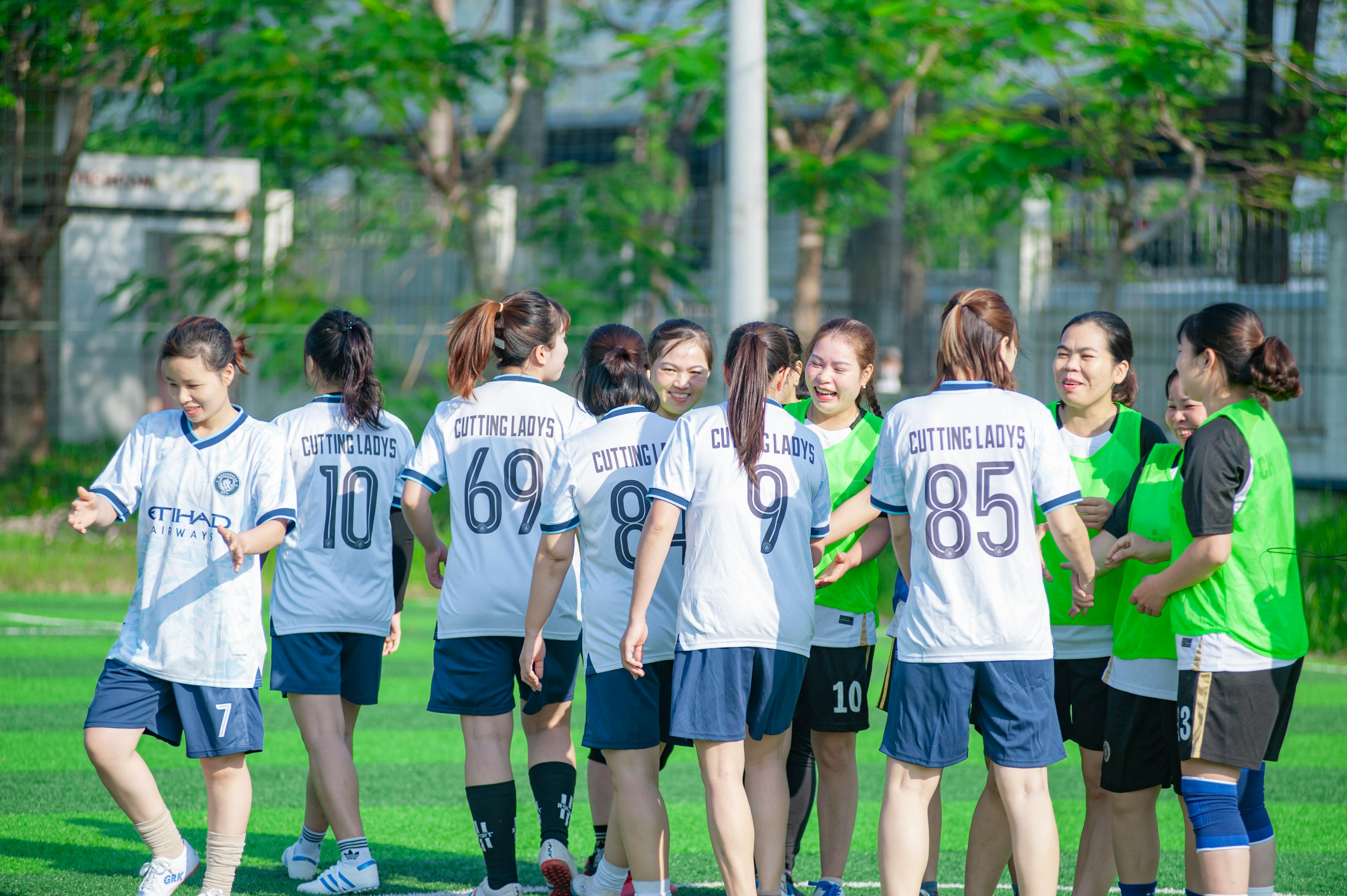 Group of women soccer players in Hanoi celebrating after a game outdoors.