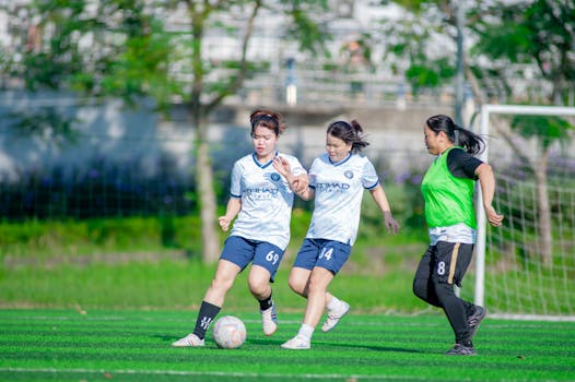 Three women playing soccer on a sunny day in Hanoi, Vietnam. Energetic and competitive.