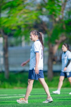 Two young women enjoying a game of soccer outdoors in Hanoi, Vietnam.