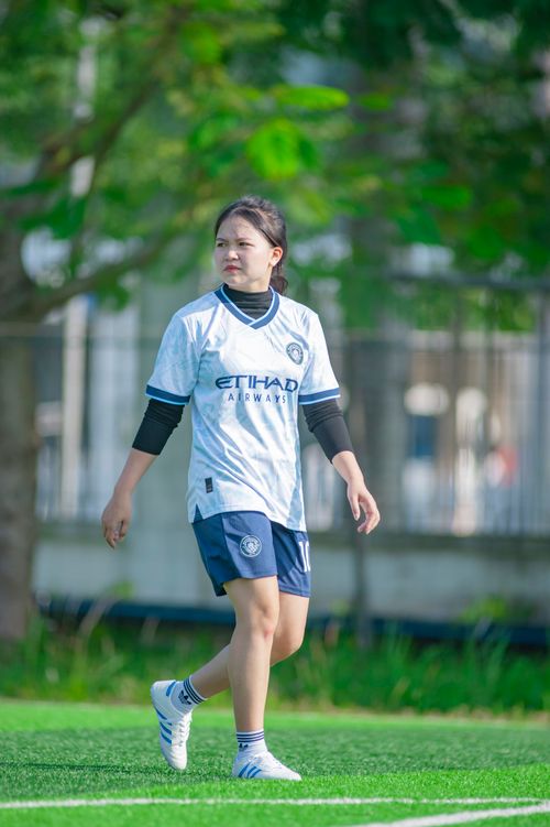 Free A young woman in a soccer outfit walking on a green field in Hanoi. Stock Photo