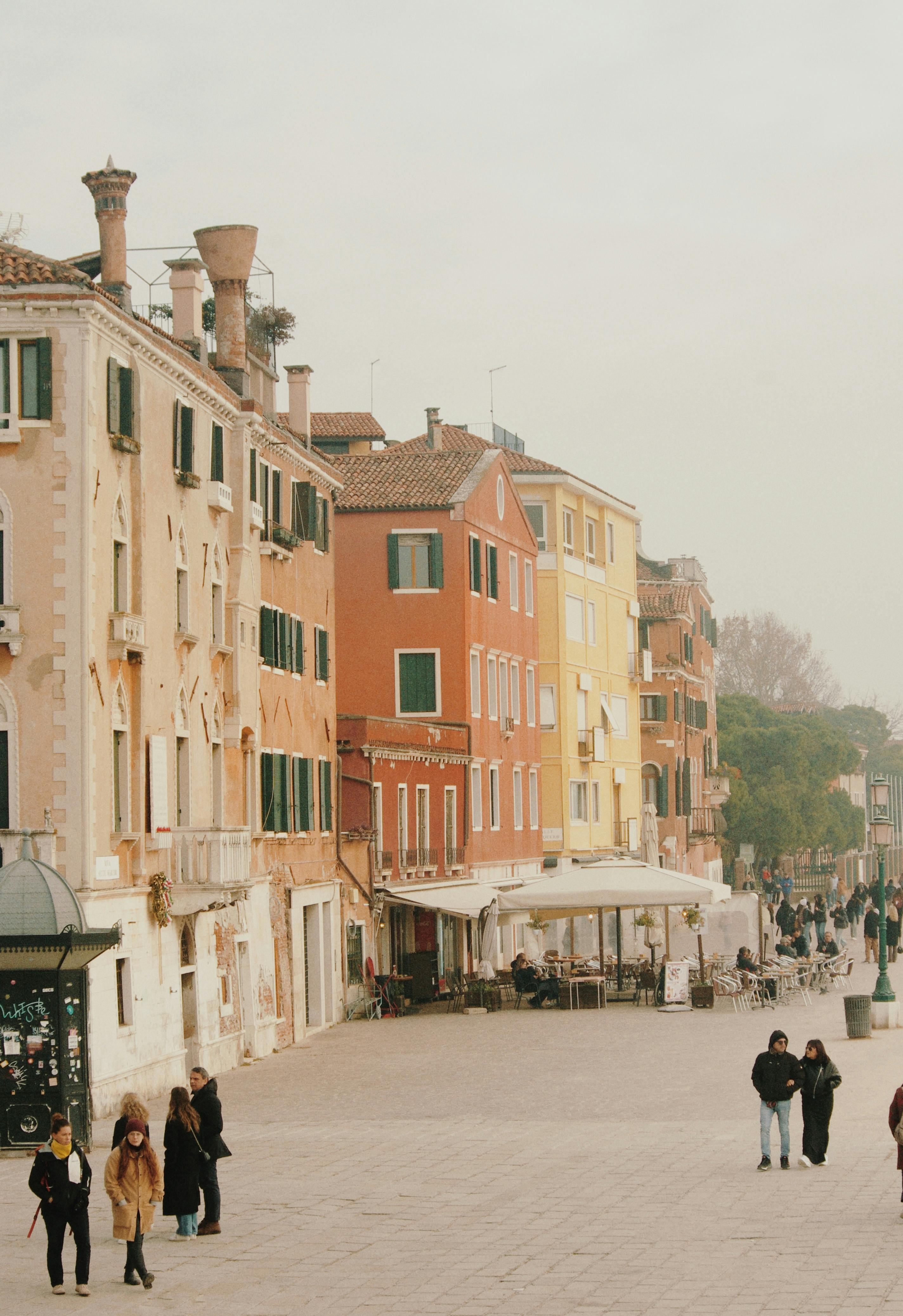 Scenic view of colorful Venetian buildings and strolling people in Venice, Italy.
