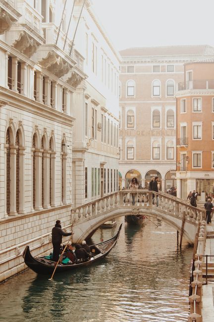 Gondola gliding under bridge in scenic Venice, showcasing charming architecture and serene canals.