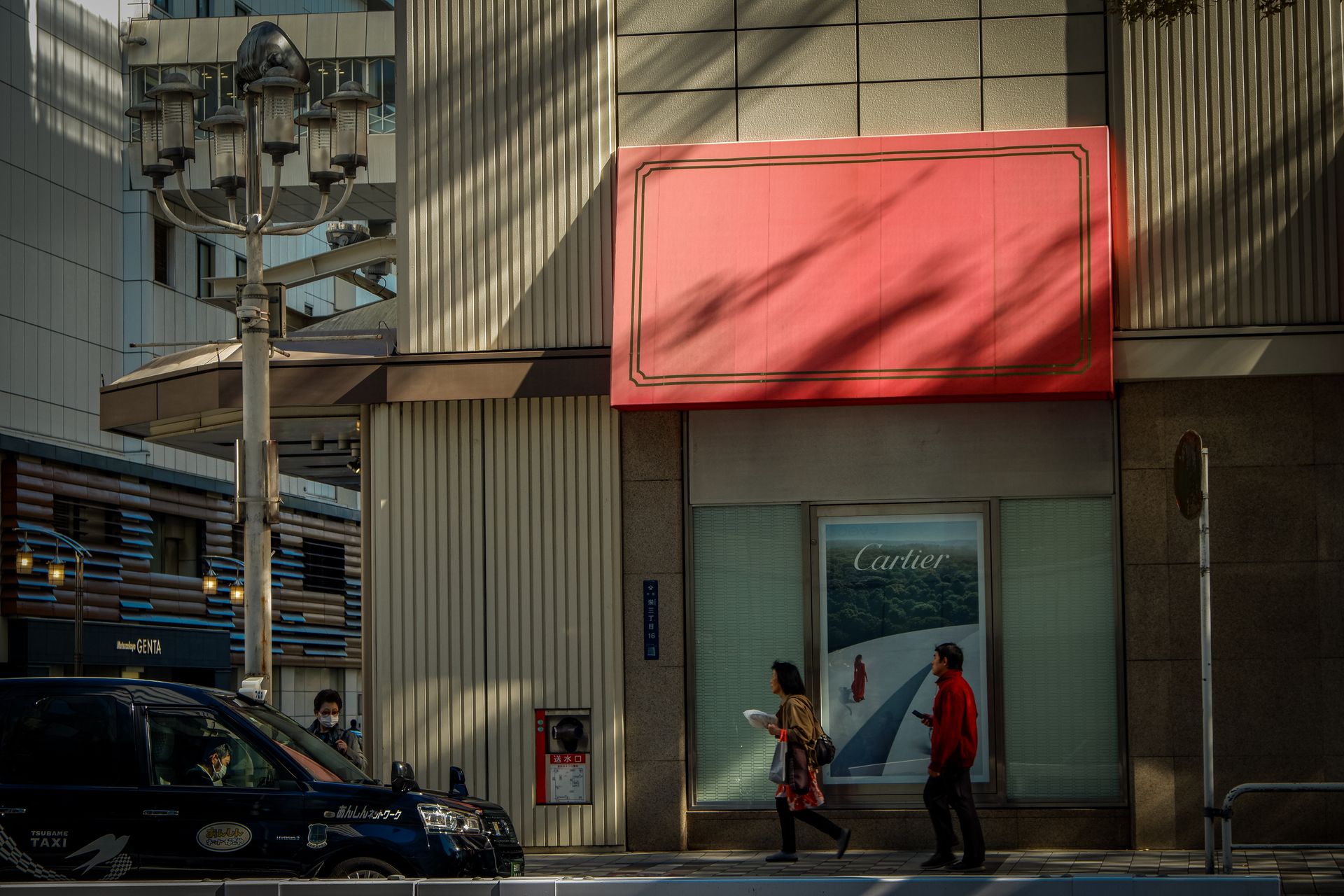 City street view featuring a Cartier storefront, pedestrians, and a taxi.